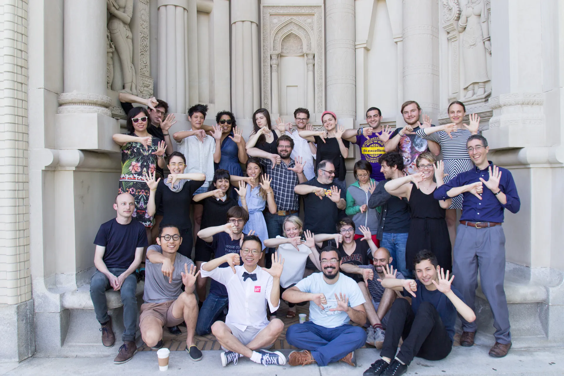 A group of participants smile and make a p5 sign with their hands